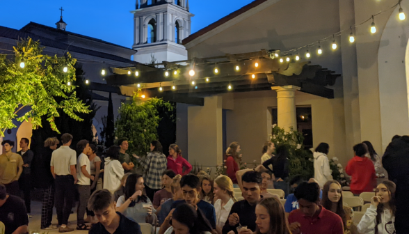 The twilight fades as students serve themselves or enjoy their floats while listening to Fr. Walshe