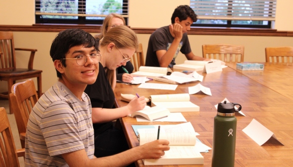 Four studying Euclid at one corner of a classroom table