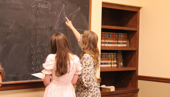 Two students practice a prop at the board together