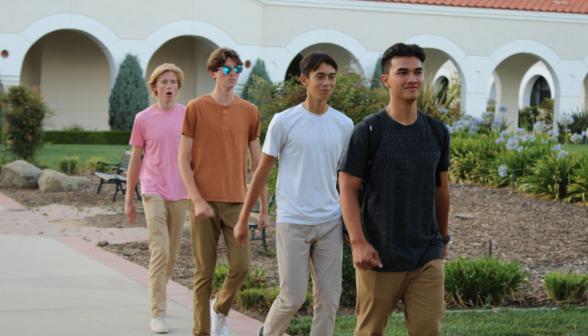 Four students walking single file from one classroom building to the other