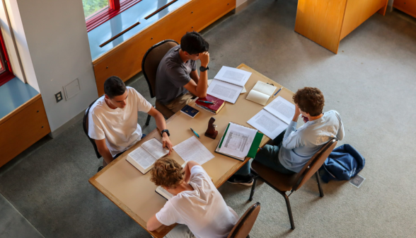 Four study at a rectangular table