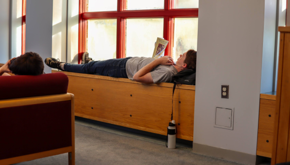 A student studies lying down on a long window ledge