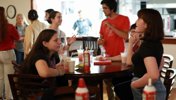 Three chat at a table over drinks