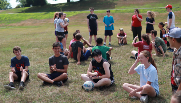 Students sit and stand around the field, chatting