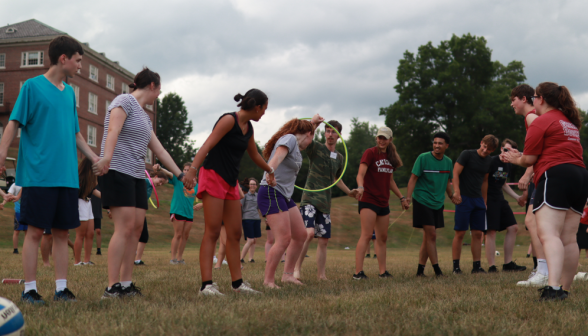 Holding hands in a line, students try to pass a hula hoop down the line