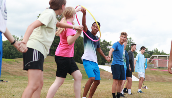 Another team passes the hula hoop