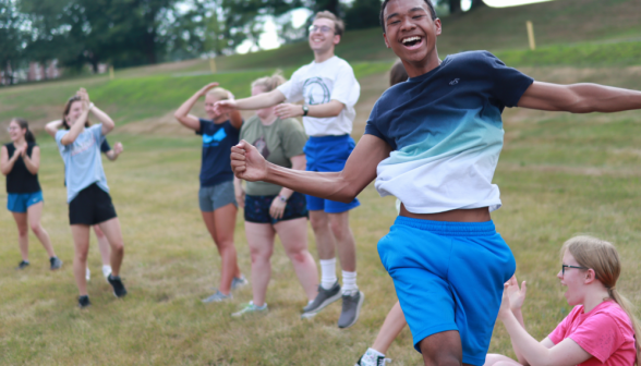 In the foreground, a student runs by the camera cheering; other students in the background also applaud