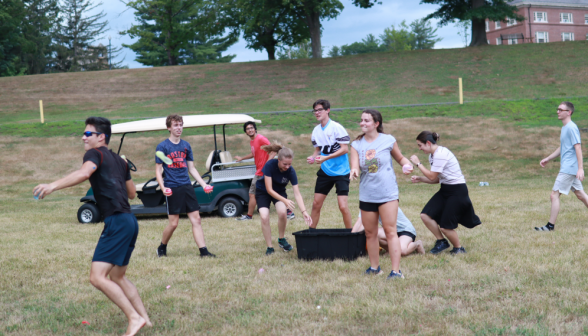 Water balloon fight! Students grab ammo from a tub of balloons