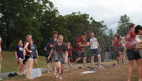 Soapy water splashes up as another student prepares to dive onto the slide