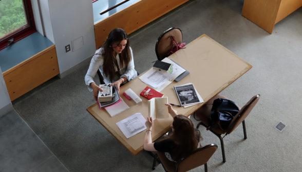 Two lay out their books at a table