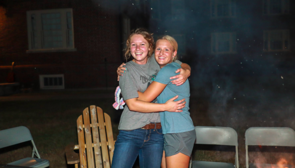 Two girls hug by a bonfire