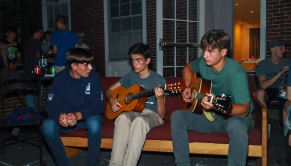 At the men's dorm: three on a couch, two play guitars