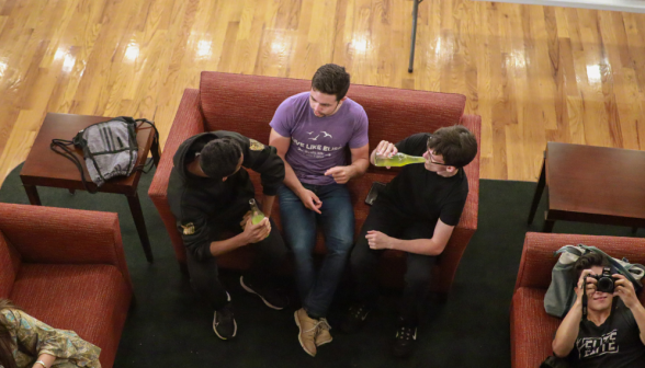 From above: three chat on a small couch, while in a corner another photographs the photographer