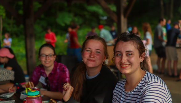 Three smile for the camera at the picnic table