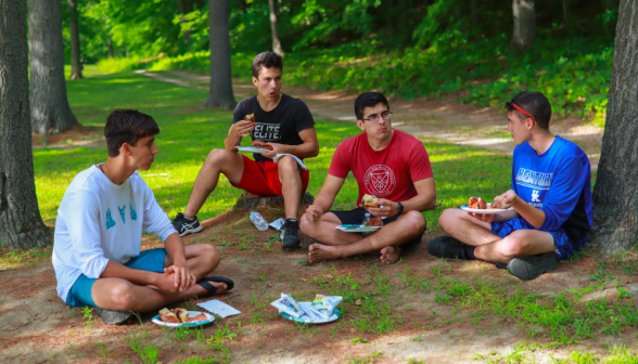 Four eat and chat cross-legged on the ground