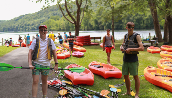 Students alongside rows and stacks of kayaks