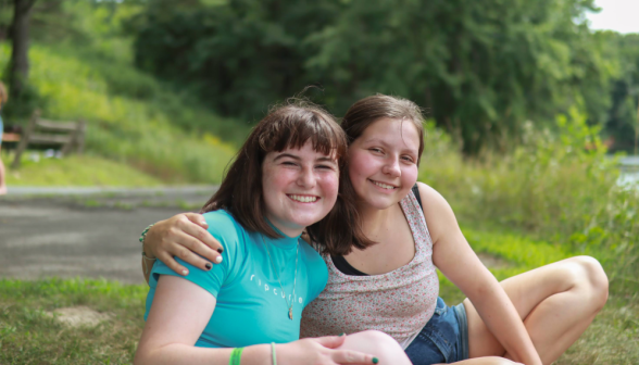 Two smile at the camera, seated