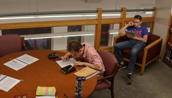 Two studying, one at a desk, one in an armchair