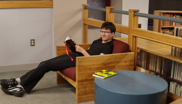 A student in an armchair smiles for the camera