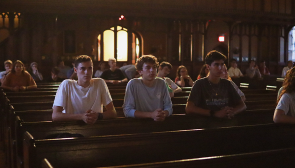 Three in a pew praying the Rosary