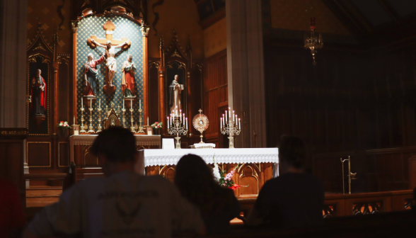 The altar, monstrance, and candelabras, with students silhouetted