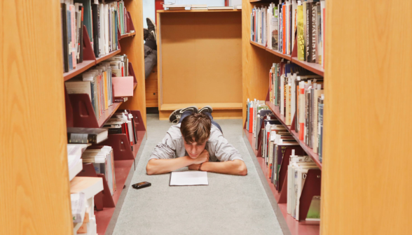 A student studies lying down in one of the aisles