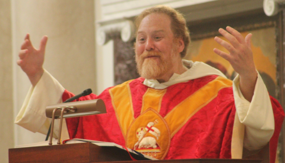 Fr. Michaels preaches, arms outstretched