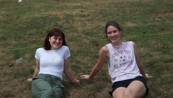 Two relaxing on the grass smile at the camera