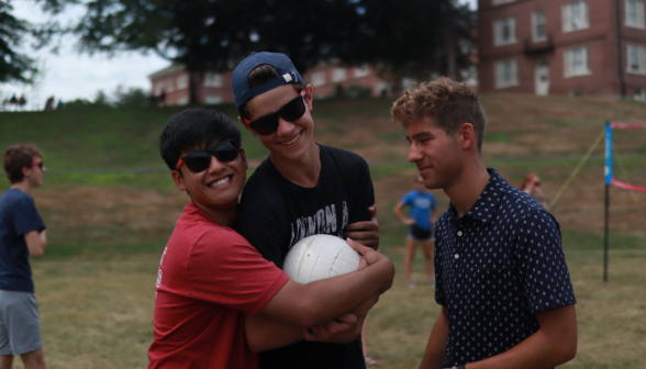 Three pose with the volleyball