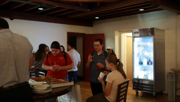 Students eat pizza around a table