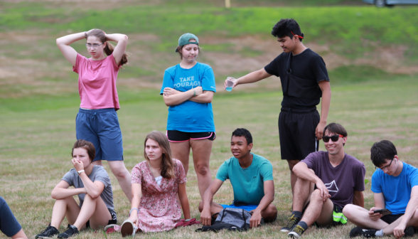 Behind the seated students, another prepares to prank one by pouring Gatorade on him