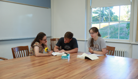 Three study Euclid at one corner of a table