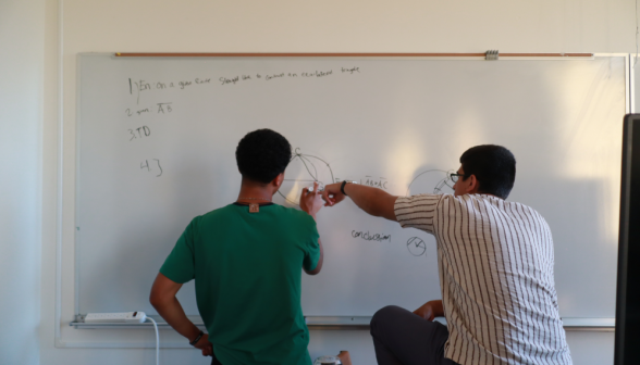 A prefect explains a prop to a student at the board