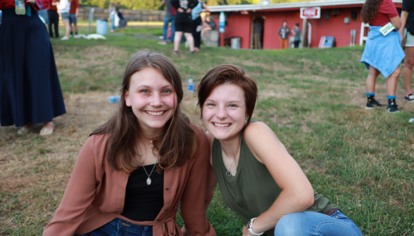 Two pose for the camera, seated on the grass