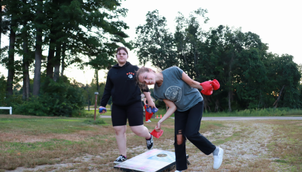 Two playing beanbags; one smiles at the camera