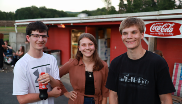 Three pose for a photo outside the snack shop