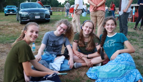 Four seated on the grass smile for the camera