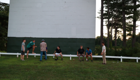 Groups of students seated on the fence or standing by it, chatting