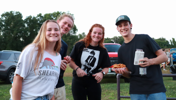 Four pose for a photo, one with food