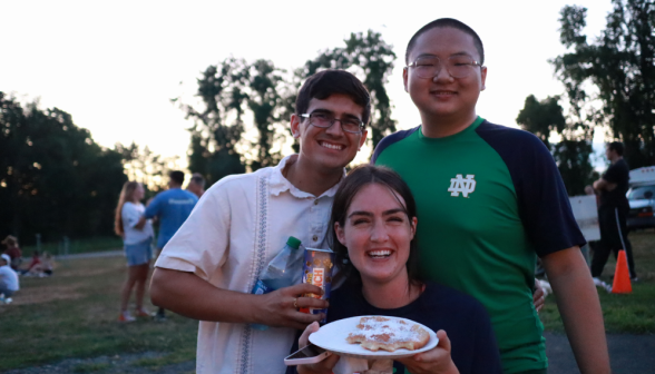 Two prefects and programmer pose for a photo with a partially-eaten friend dough