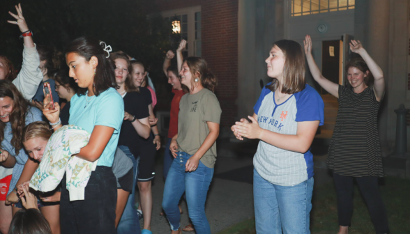 The women emerge from their dorm to listen