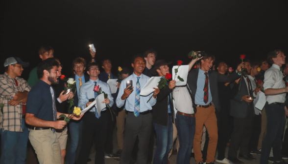 The men hold out their roses