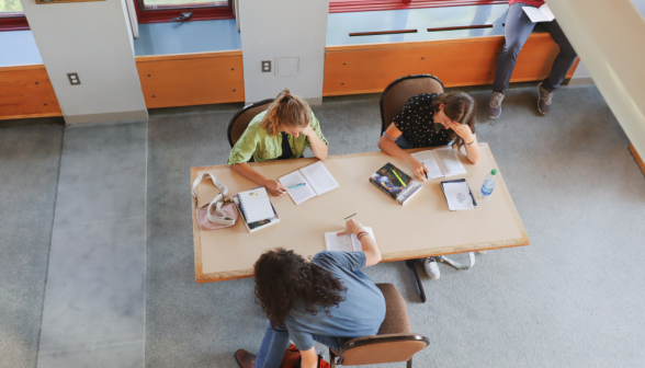 Three study at a rectangular table