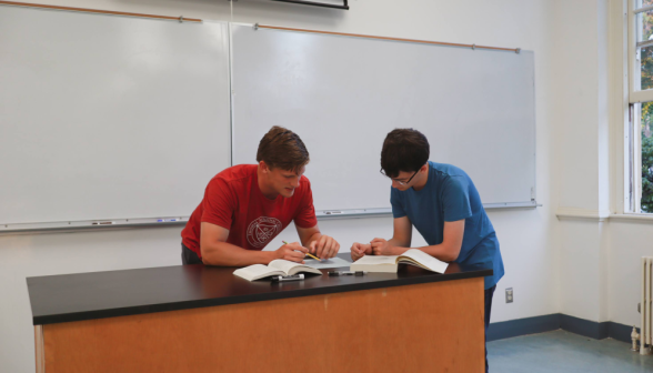 Two discuss props at a chemistry table