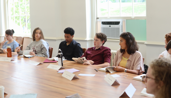 The students listen to someone out of frame making a point