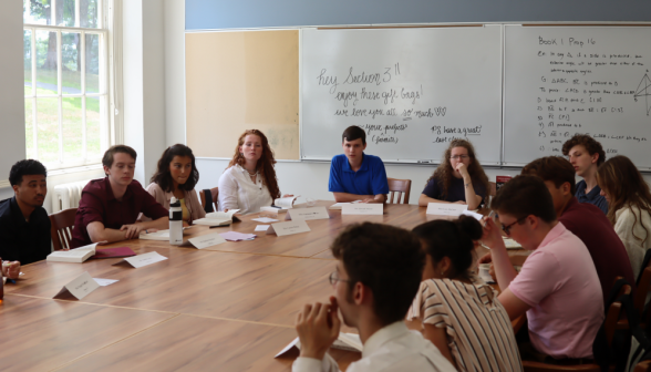 The students listen to someone out of frame making a point