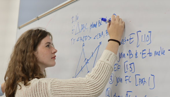 A student practices I.16 at the whiteboard