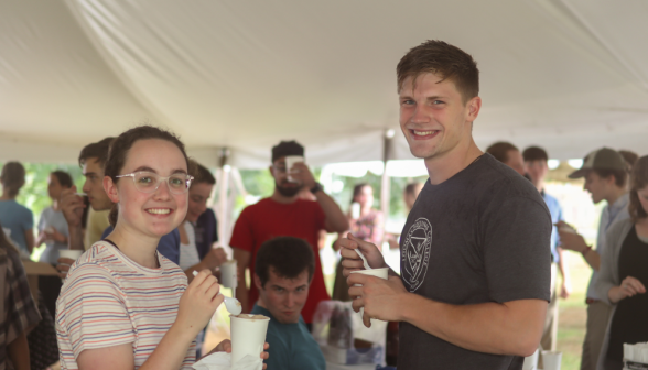 Two smile for a camera, with a third making a face in the background