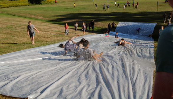 Students and tutor kids go down the slip 'n' slide