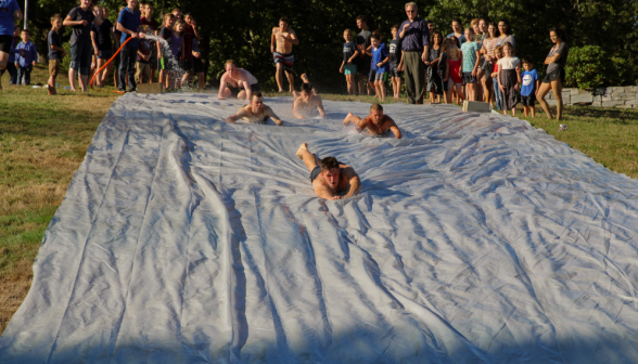 Students in swimwear zip down the slide